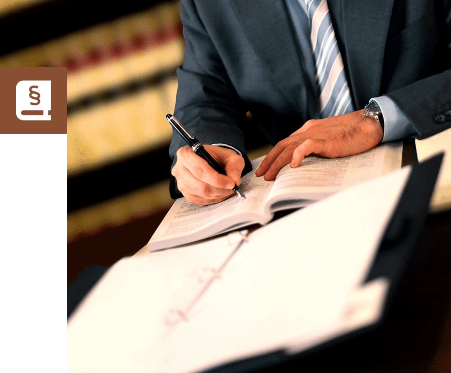 A man in suit writing on paper with pen.