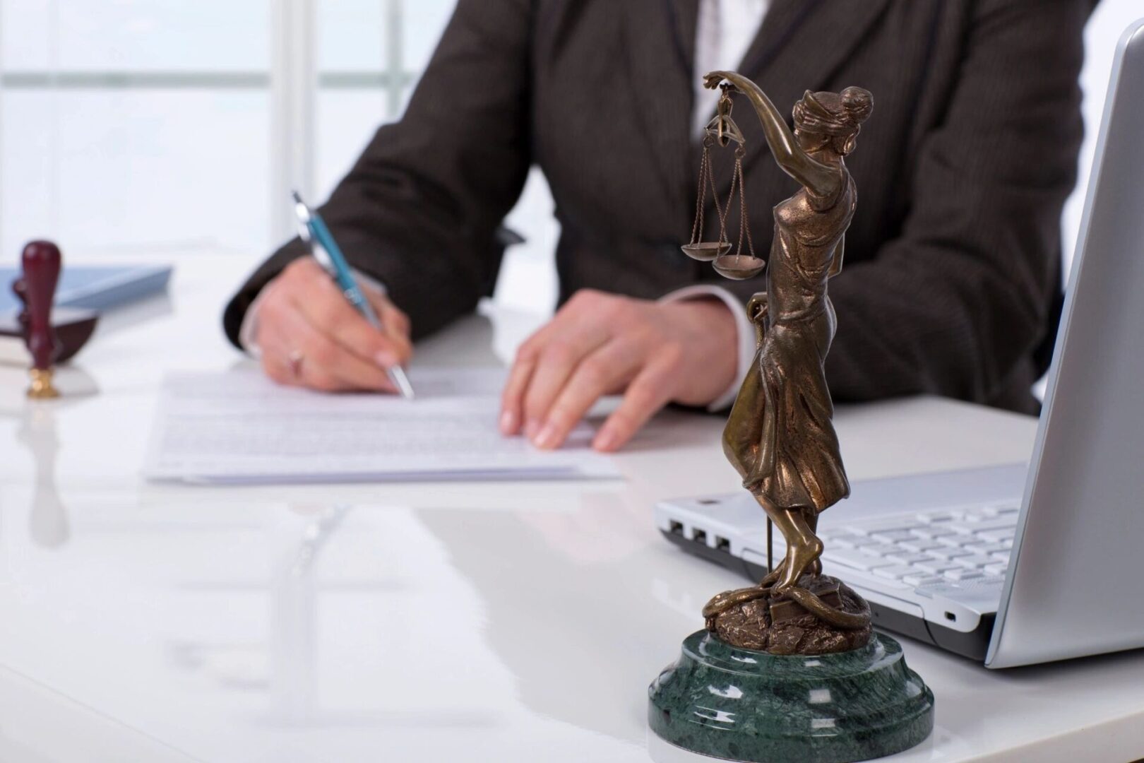 A person writing on paper next to a statue.