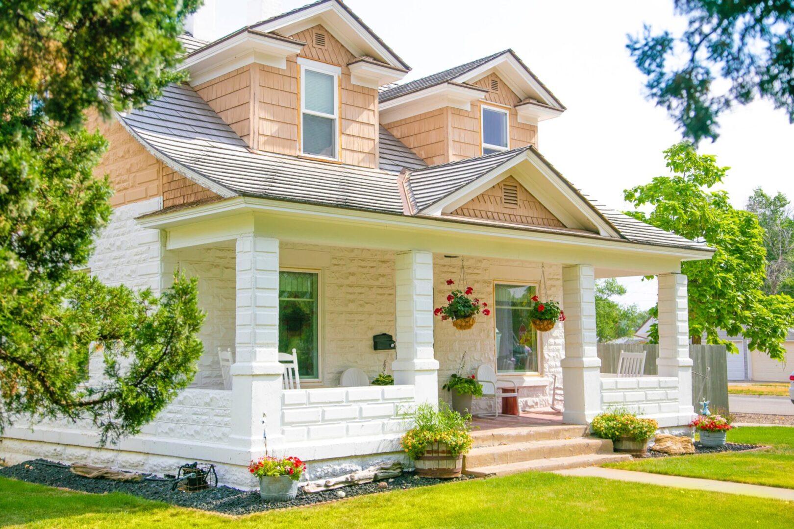 A house with a porch and flower pots on the front of it.