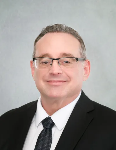 A man in a suit and tie smiling for the camera.